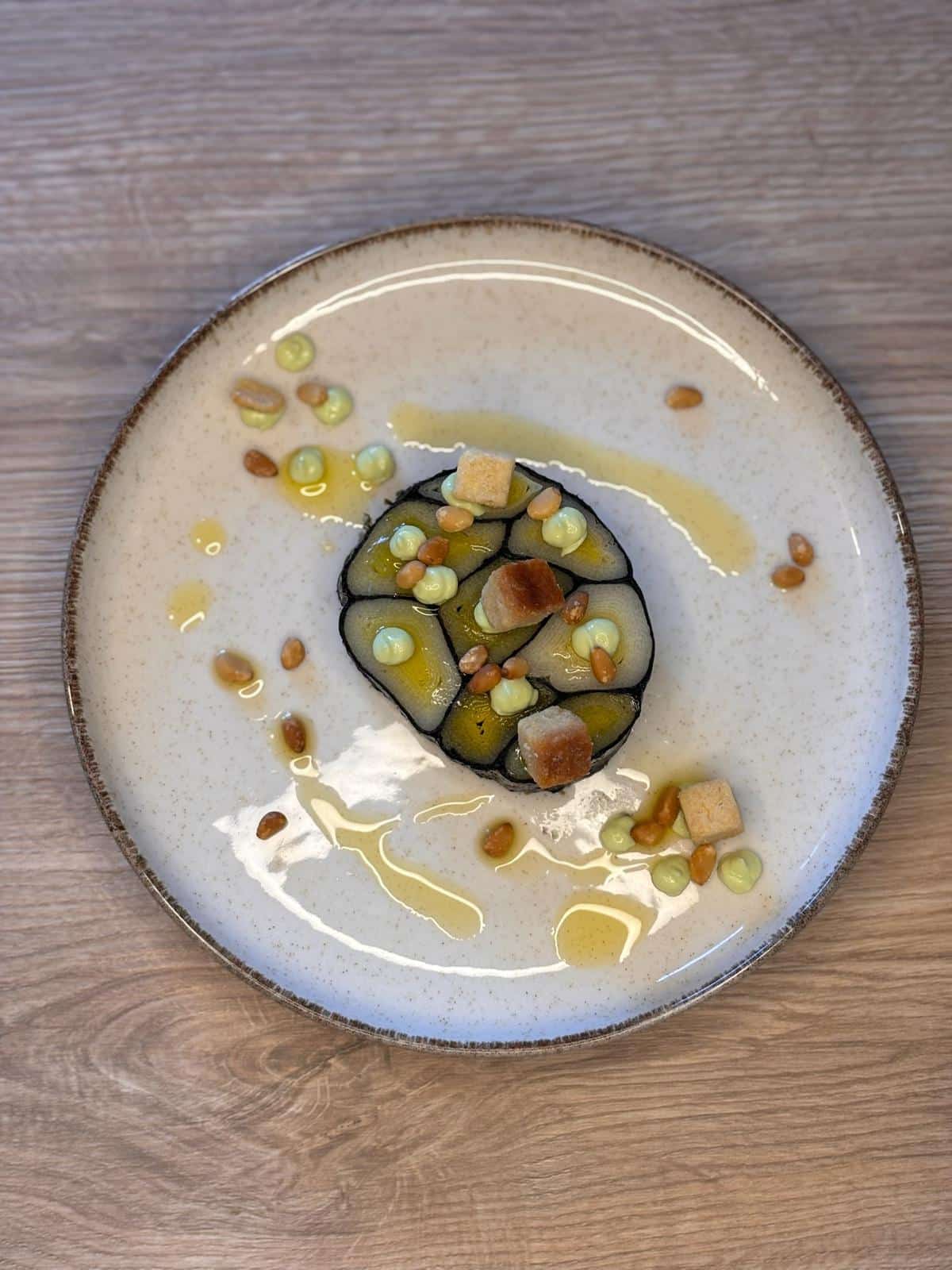 Plat gastronomique avec légumes en gelée, crème, pignons et croûtons délicatement dressé